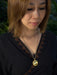Woman wearing a gold necklace with a pendant outdoors