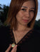 Woman holding a gold necklace with a pendant against a blurred outdoor background