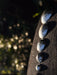 Hammered metal stones arranged on a dark surface with a blurred natural background