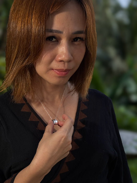 Woman wearing a black top with a patterned design, holding a white object.
