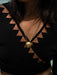 Gold necklace with a spherical pendant on a person wearing a black top with geometric patterns.