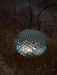 Metallic pendant with textured surface on a dark background