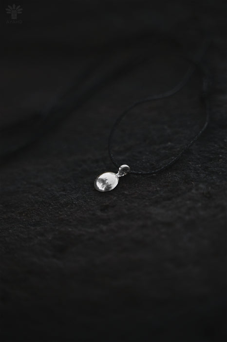 Silver pendant on a dark textured fabric background