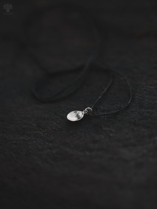 Silver necklace with a pendant on a dark textured surface