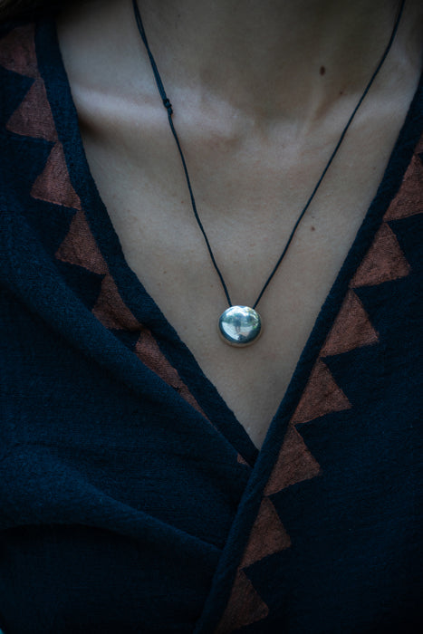 Necklace with a pendant on a person wearing a dark top.