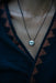Necklace with a pendant on a person wearing a dark top.