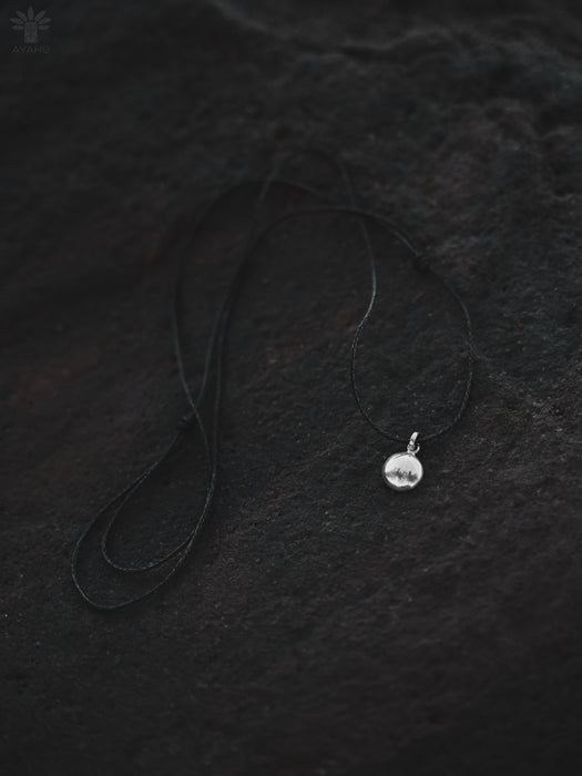 Silver necklace with a pendant on a textured black surface