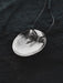 Silver pendant necklace on a dark textured background