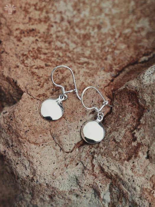 Silver earrings on a textured stone surface