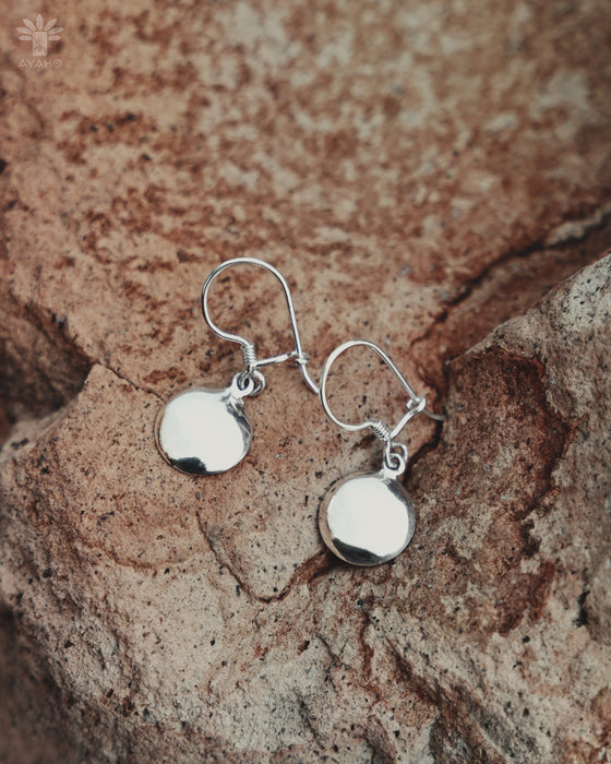 Silver earrings on a textured stone surface