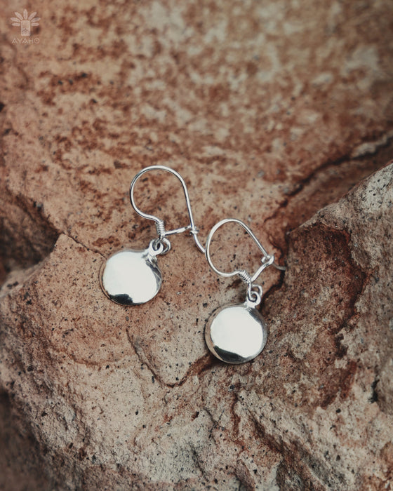Silver earrings on a textured stone surface