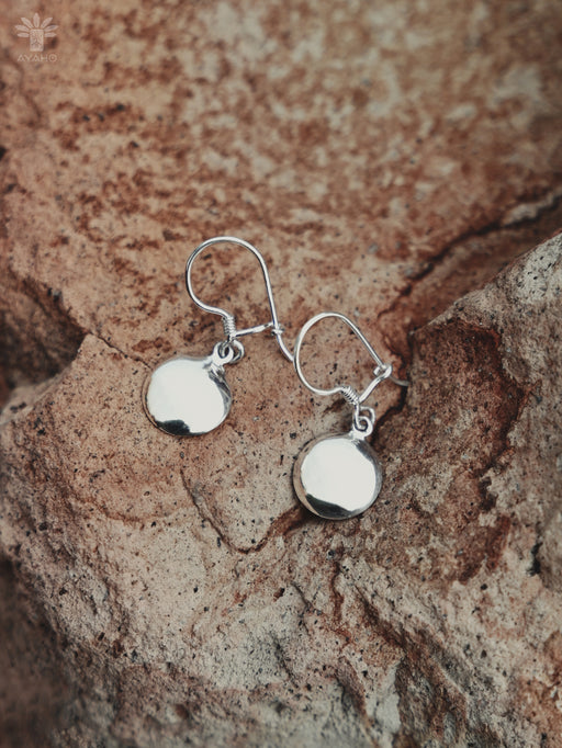 Silver earrings on a textured stone surface