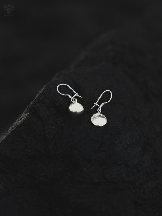 Silver earrings on a textured black surface