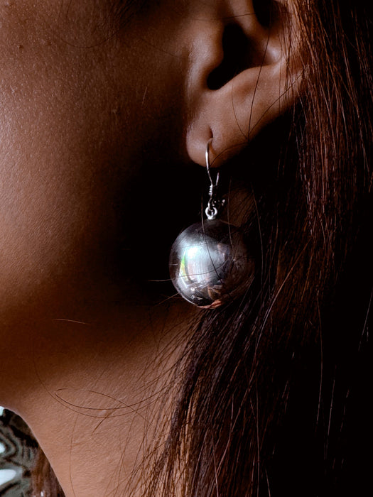 Close-up of an earring worn by a person with dark hair.