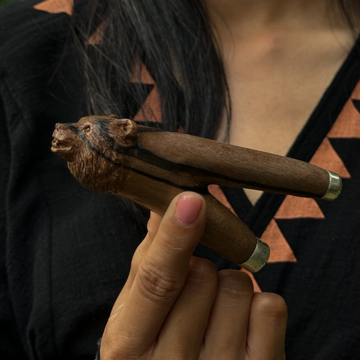 Handcrafted wooden kuripe featuring a powerful bear totem, placed beside a traditional hapé bottle in natural sunlight.