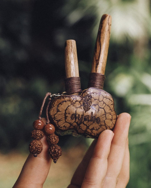 Sacred Ayahuasca vine kuripe pipe adorned with rudraksha and goldstone, a handcrafted symbol for hape snuff rituals, nestled in natural greenery.