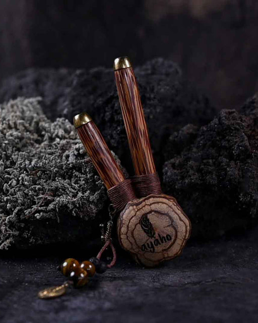A hand presents a wooden kuripe pipe, meticulously handcrafted for hape snuff application This unique smoking accessory, with its necklace design and rustic charm, exemplifies traditional shamanic tools and doubles as a protective herbal medicine kit