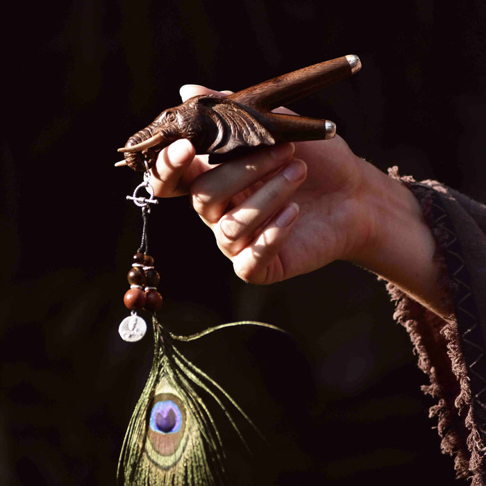 a wooden kuripe elephant pipe, designed for hape snuff application. The kuripe, linked to a charm-adorned necklace, serves as a unique, handmade smoking accessory and part of a shamanic protection kit, blending herbal medicine traditions