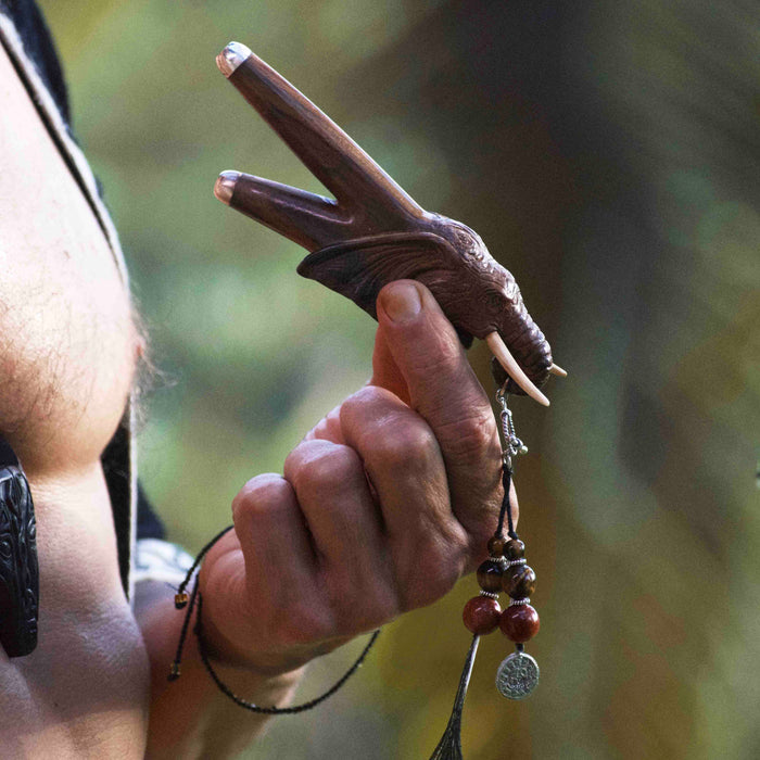 a wooden kuripe elephant pipe, designed for hape snuff application. The kuripe, linked to a charm-adorned necklace, serves as a unique, handmade smoking accessory and part of a shamanic protection kit, blending herbal medicine traditions