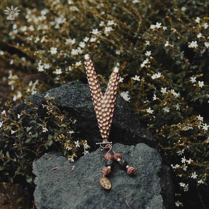 Golden Kuripe pipe, a ceremonial hape snuff applicator and shamanic tool, displayed as a necklace on weathered wood. Unique handmade smoking accessory for herbal medicine