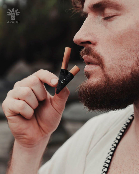 Man holding a black and orange Ayahobrush against his face