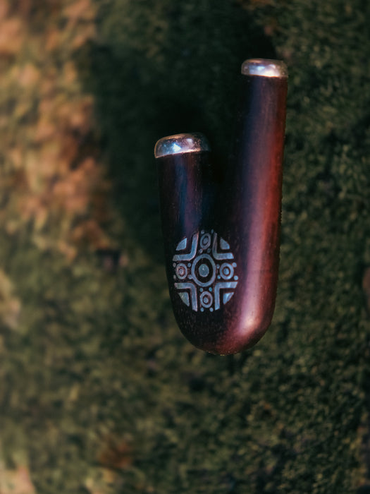 Wooden pipe with metallic accents on a textured green surface