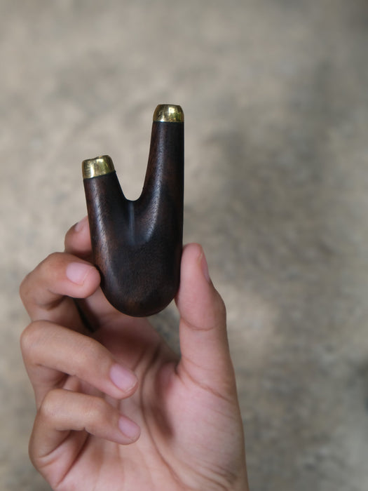 Hand holding a wooden object with gold tips against a neutral background