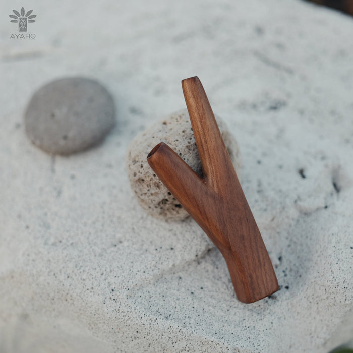 Two wooden sticks on a sandy surface with 'AYAHQ' branding.