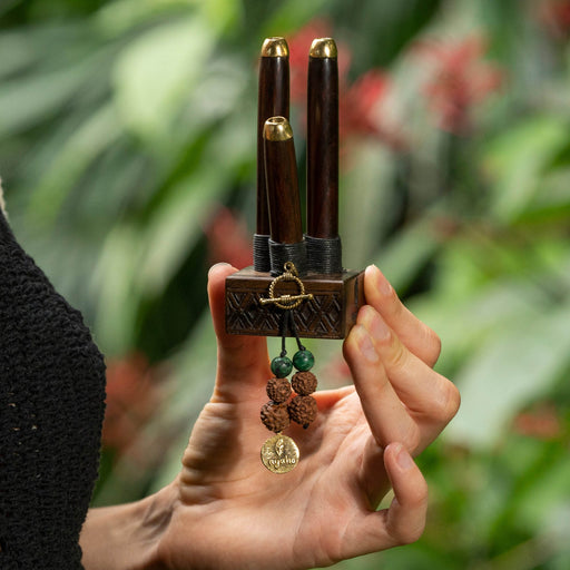 Rose wood kuripe pipe necklace with a protective Shipibo ornament, presented on a carved wooden hand, symbolizing high-quality shamanic heritage