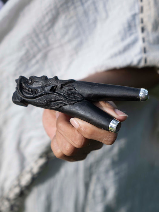 Hand holding a black ornate object with intricate designs.