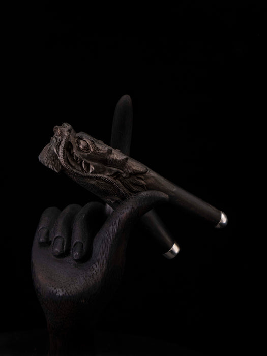 Dark stone sculpture of a hand holding a branch against a black background