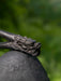 Close-up of a dragon head sculpture on a stone sphere with a blurred green background