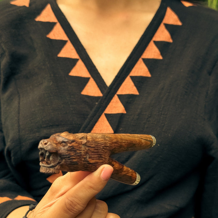 Person holding a wooden animal figurine against a dark background with geometric patterns