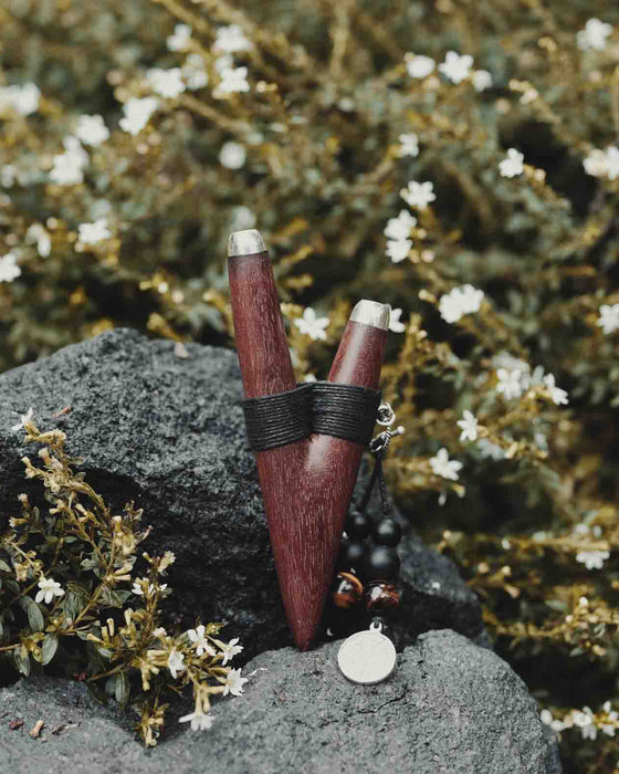 A serene woman holds a high-quality wooden kuripe blowpipe, used as a hape snuff applicator. The kuripe, doubling as a necklace with detailed charms, represents both a shamanic tool and a unique gift.