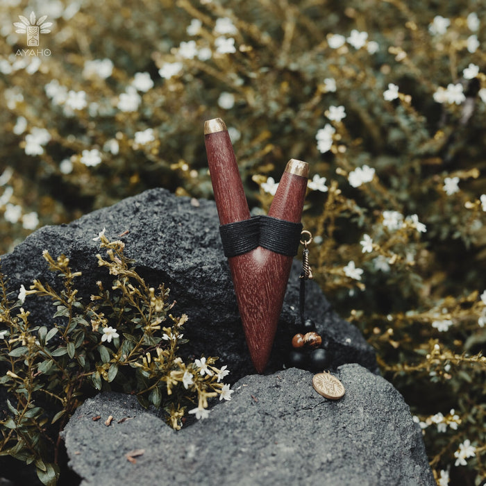 A serene woman holds a high-quality wooden kuripe blowpipe, used as a hape snuff applicator. The kuripe, doubling as a necklace with detailed charms, represents both a shamanic tool and a unique gift.