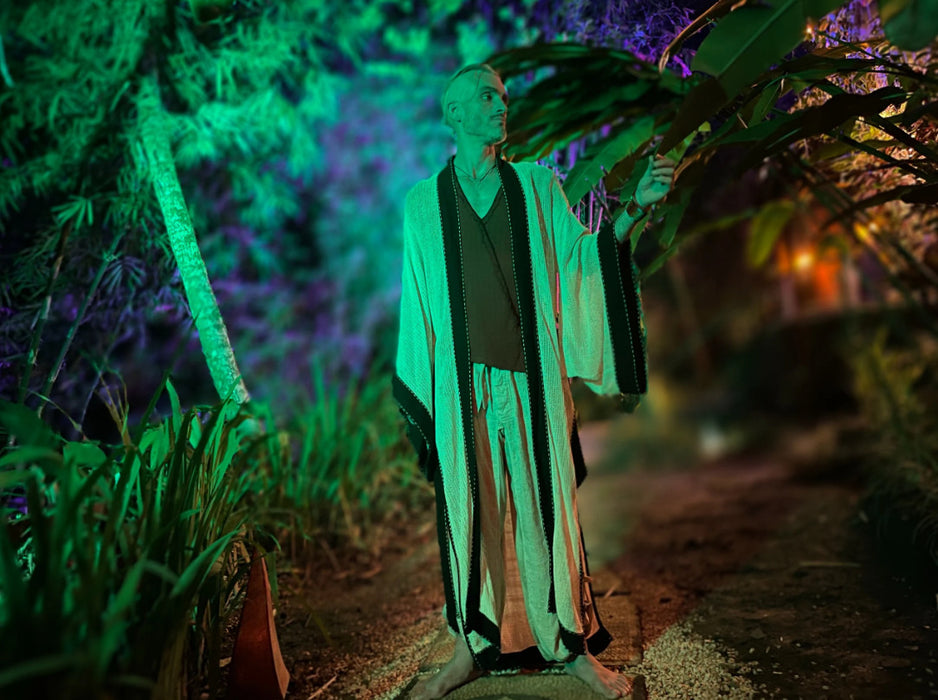 A figure stands poised on a boat, draped in a long cotton shibori kimono cardigan, embodying the chic spirit of Boheme as a ritual robe and beach coverup