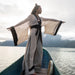 A figure stands poised on a boat, draped in a long cotton shibori kimono cardigan, embodying the chic spirit of Boheme as a ritual robe and beach coverup