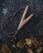 Golden Kuripe pipe, a ceremonial hape snuff applicator and shamanic tool, displayed as a necklace on weathered wood. Unique handmade smoking accessory for herbal medicine