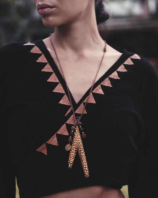 Golden Kuripe pipe, a ceremonial hape snuff applicator and shamanic tool, displayed as a necklace on weathered wood. Unique handmade smoking accessory for herbal medicine