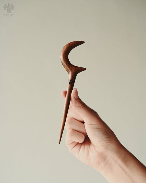 Durable teak moon clip with polished edges, securing a thick updo with effortless elegance.