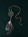Tiny handcrafted dream catcher pendant on a leather cord, resting on a bed of dried lavender and crystals