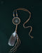 Tiny handcrafted dream catcher pendant on a leather cord, resting on a bed of dried lavender and crystals