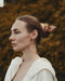 Close-up of the leaf-shaped hairpin’s textured wood grain, pinned into a braided hairstyle for a natural boho look