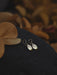 Compact bronze mirror studs in a suede pouch, ideal for on-the-go spiritual protection.