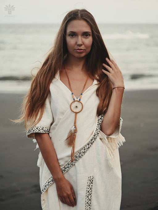 Small dream catcher amulet attached to a backpack zipper, photographed during golden hour in a forest