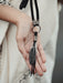 Black raven feather encased in resin with silver wire wrapping, hanging from a black leather choker for an edgy spiritual look