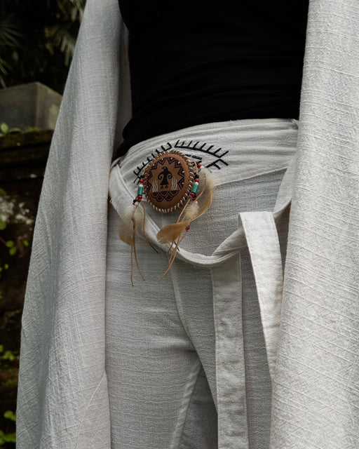 Handcrafted eagle feather brooch with painted details, symbolizing earth energy and spiritual transition, pinned to a tribal-printed shawl