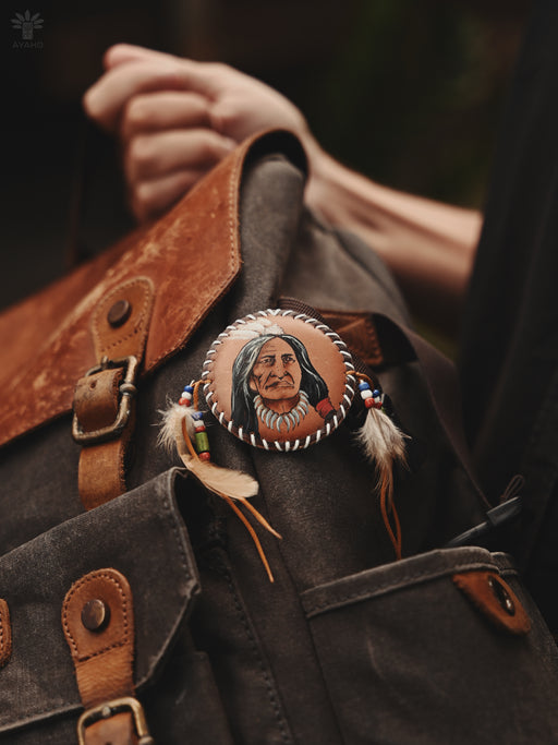 Hand-tied wild goose feather brooch with bone charms, resting beside sage and a smudging bowl for ritual use.