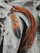 Hand-wrapped hawk feather amulet with leather cord and bone beads, resting on a bed of sacred tobacco and dried herbs
