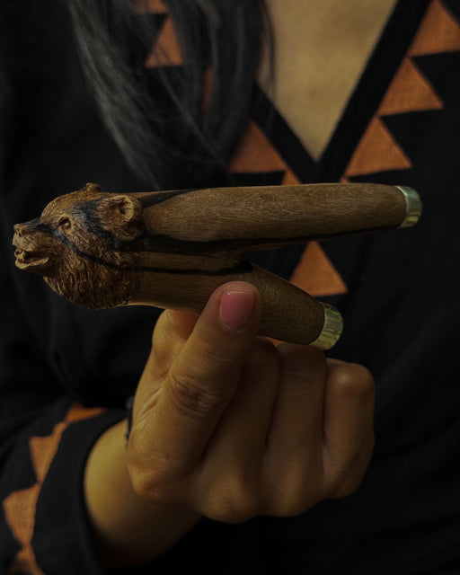 Detailed view of a bear-shaped kuripe's mouthpiece, highlighting the smooth polished wood and symbolic carvings.